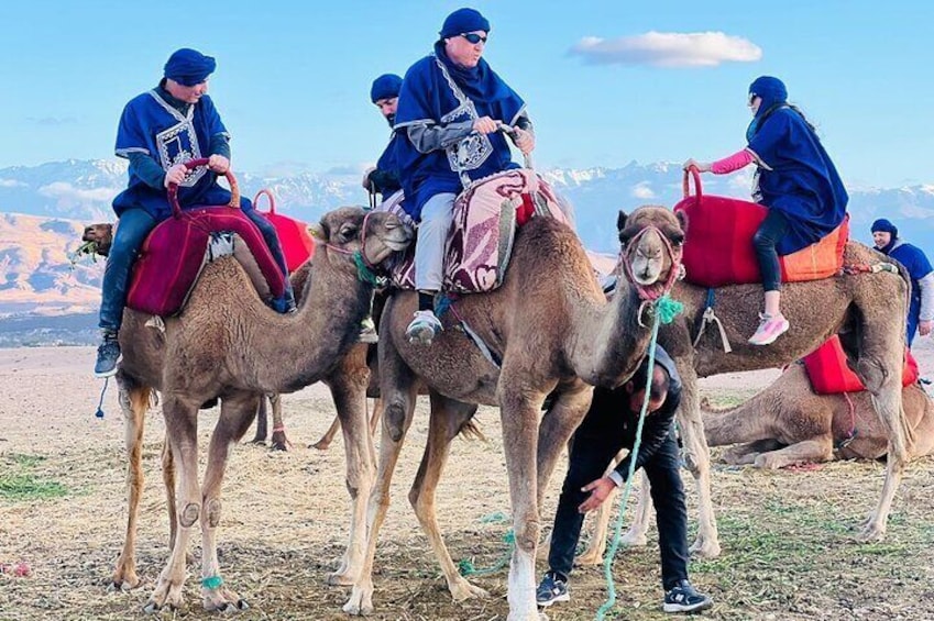 Personas montando camellos en un paisaje desértico con montañas al fondo. 1