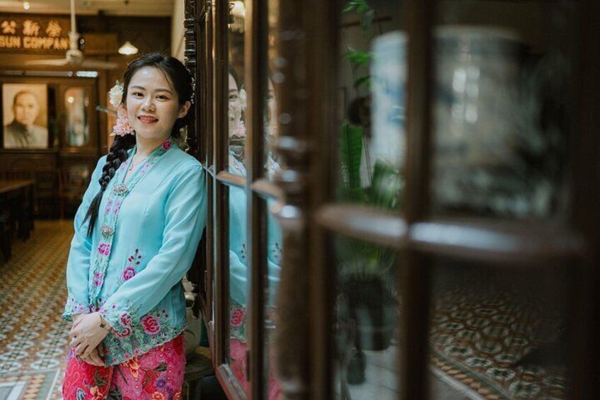 A person in traditional attire standing in a room with patterned flooring and a glass door. 4
