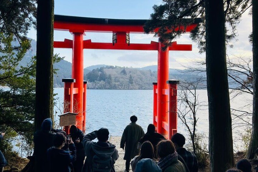 Un torii rojo, un grupo de personas y un lago. 4