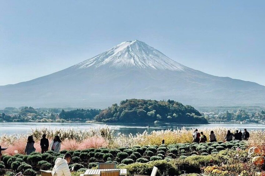 A volcano with a lake in the foreground and people walking around. 2