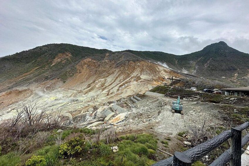 A mining site with exposed earth, a blue vehicle, and a mountain in the background. 3