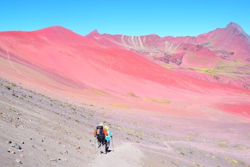 A hiker on a rocky trail with a colorful mountain range in the background. 2