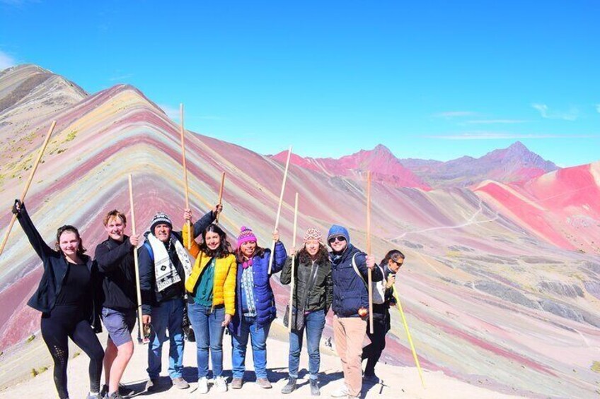A group of people standing on a mountain ridge with colorful rock formations in the background. 1