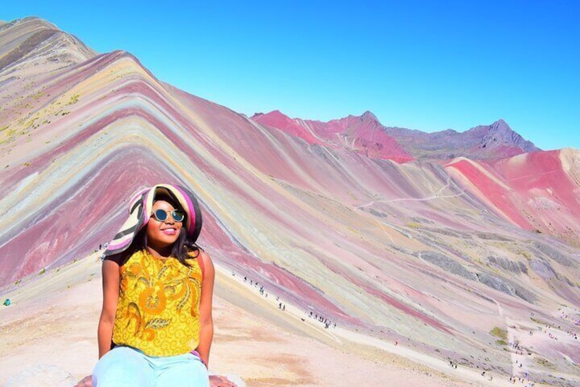 A person sitting on a colorful, striped hill with a clear blue sky in the background. 3