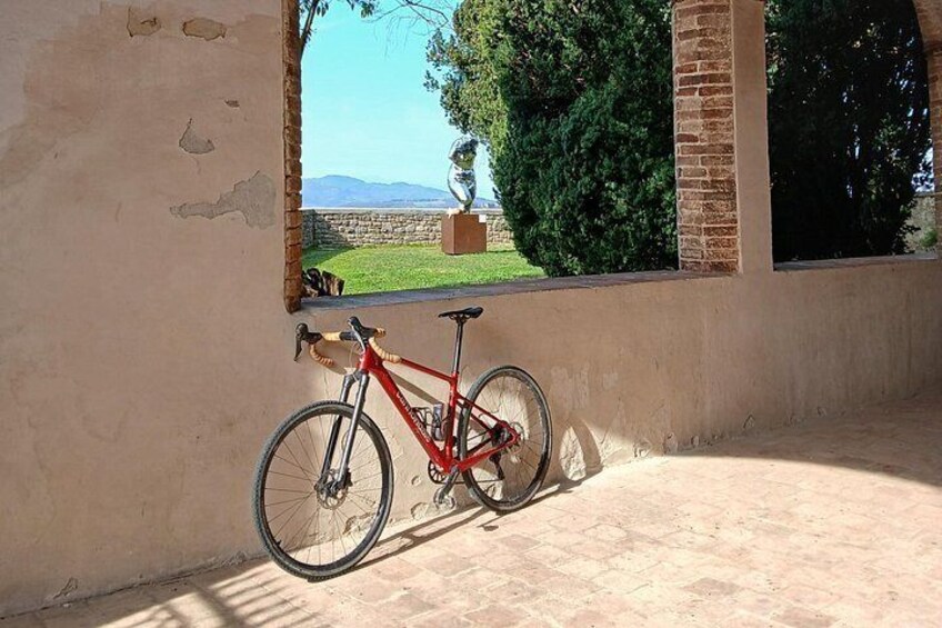 A red bicycle leaning against a wall with a window overlooking a grassy area and trees. 4