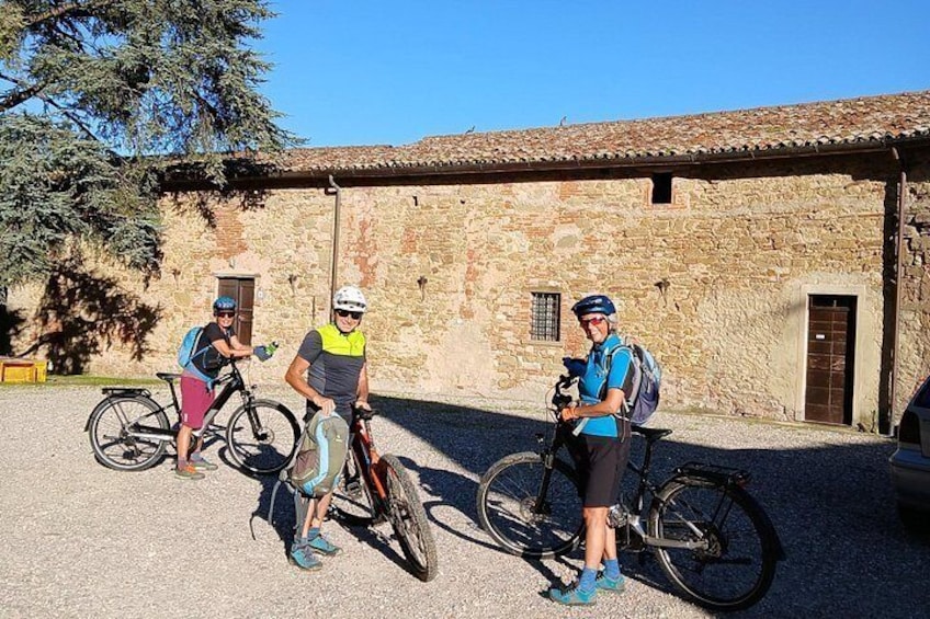 Three cyclists in front of a stone building with a tiled roof. 5
