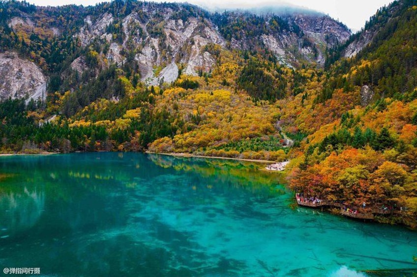 A lake surrounded by autumn-colored trees and rocky mountains. 4
