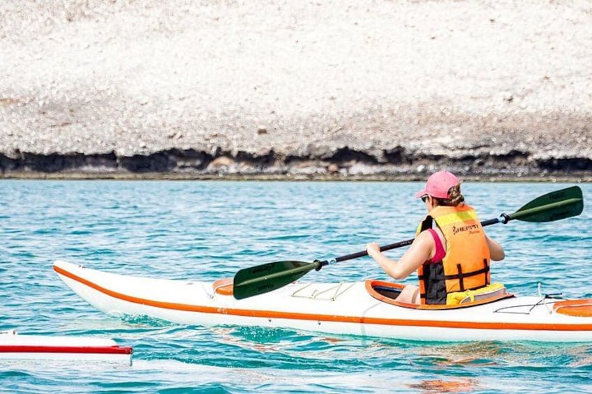Une personne pratiquant le kayak sur une étendue d’eau, avec une côte rocheuse en arrière-plan. 2