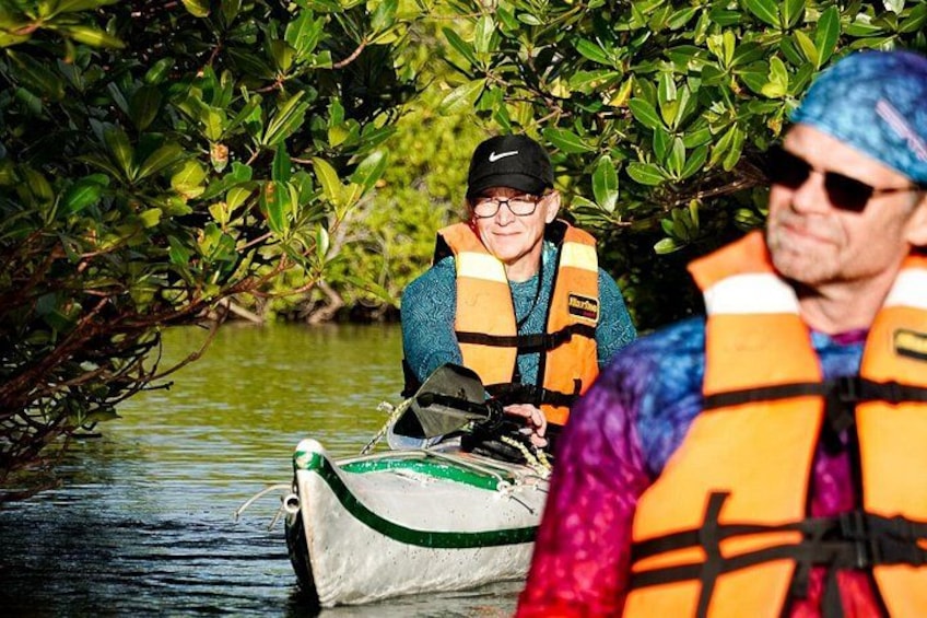 People in a boat wearing life jackets, surrounded by water and greenery. 4