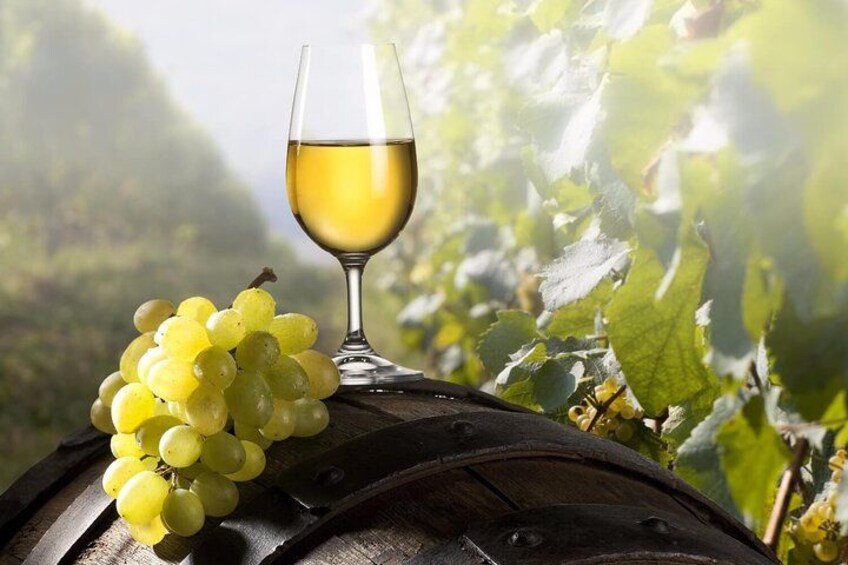 A wine barrel, a glass of white wine, and a bunch of green grapes. 2