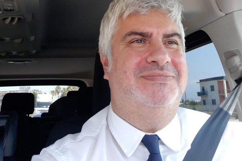 Un homme vêtu d’une chemise blanche et d’une cravate bleue, assis dans une voiture. 2