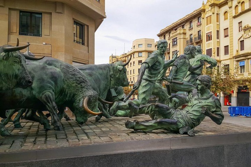 A bronze sculpture of bulls and humans in a public square. 1