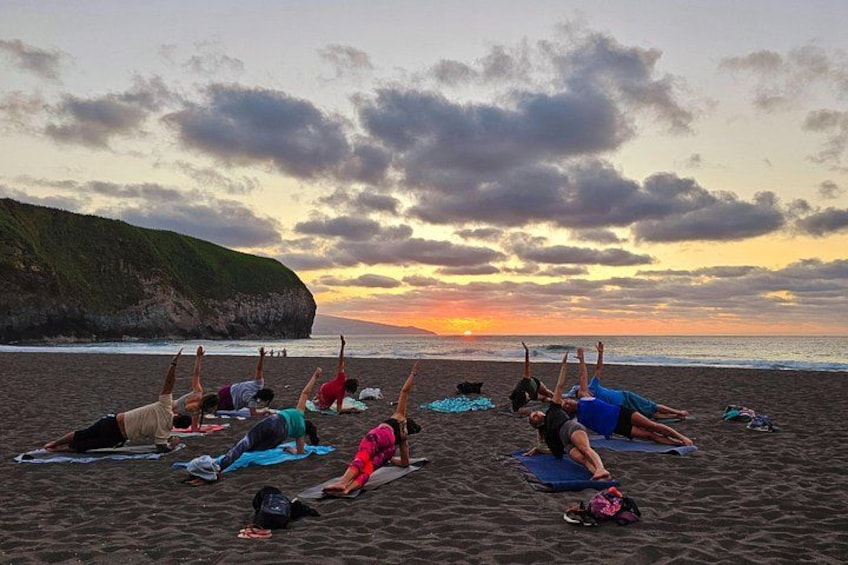 A group of people doing yoga on mats on a beach at sunset. 4