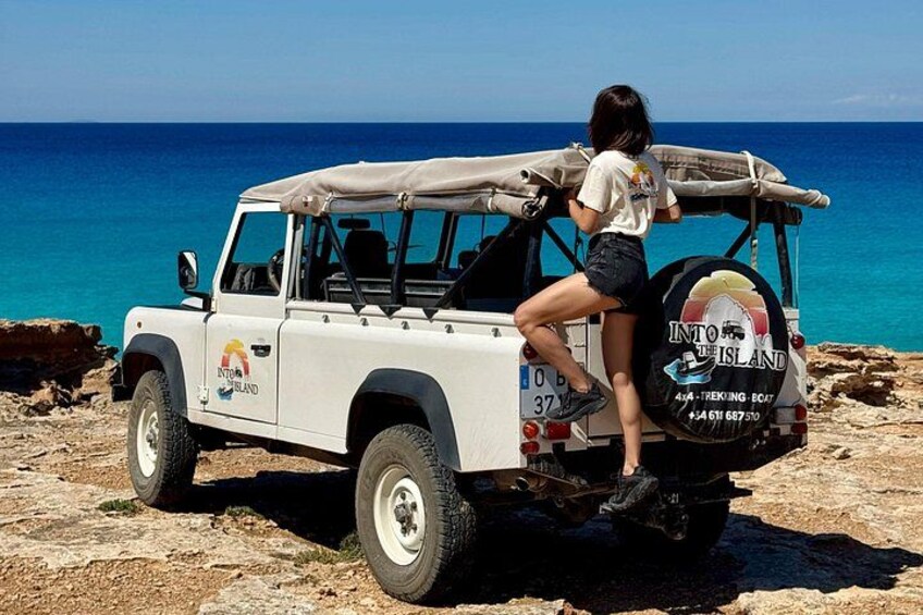 A white off-road vehicle parked on rocky terrain near a body of water. 2