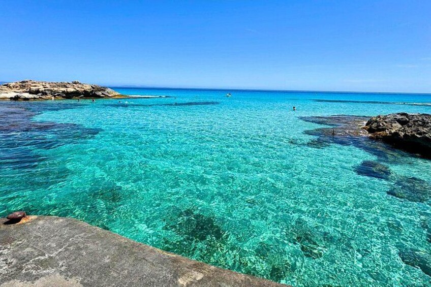 A clear turquoise sea, rocky coastline, and a distant horizon. 3