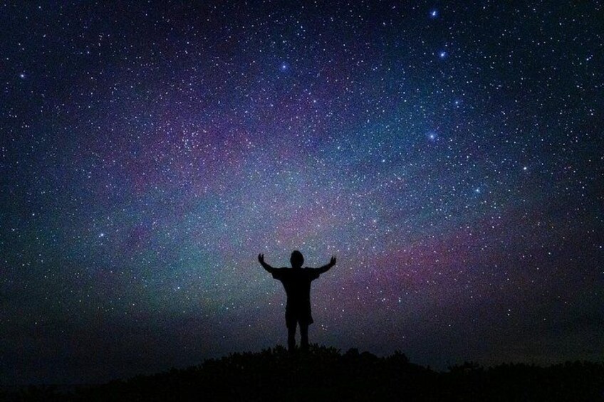 A silhouette of a person with arms raised against a starry night sky. 5