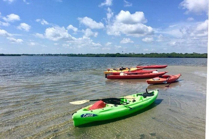 Kayaks on a sandy beach near calm water. 2