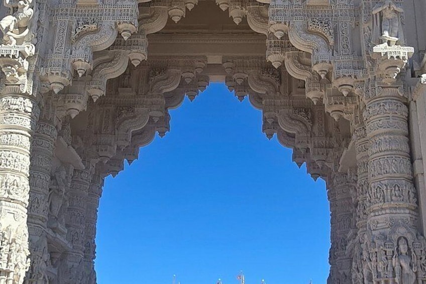 An intricately carved stone archway with detailed artwork and a clear blue sky in the background. 3