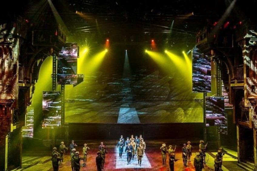 A stage with a group of people, a large screen, and stage lighting. 4