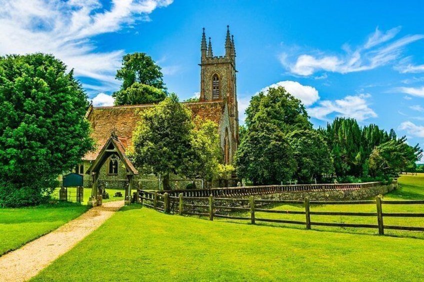 A church with a tall tower, surrounded by lush green grass and trees. 2