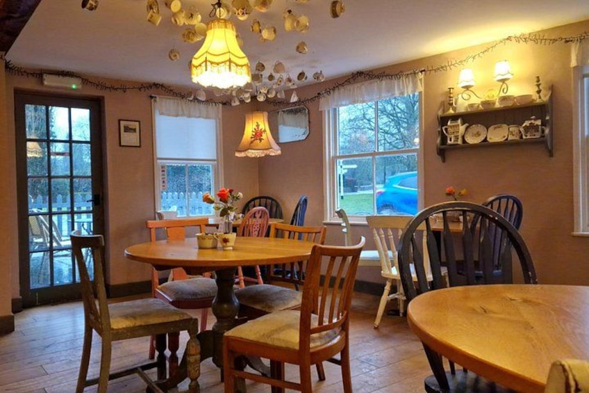 Un coin repas accueillant, avec des tables et des chaises en bois, un lustre et une fenêtre donnant sur l’extérieur. 4