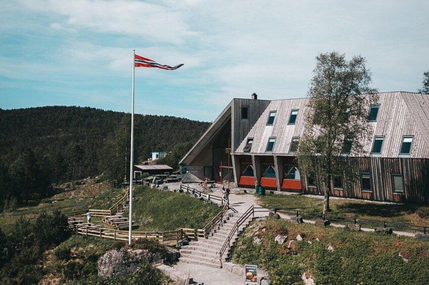 En moderne bygning med saddeltag, flagstang med flag og en trappe til indgangen. 3