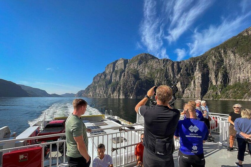 En båd med passagerer, der fotograferer et bjerglandskab. 1