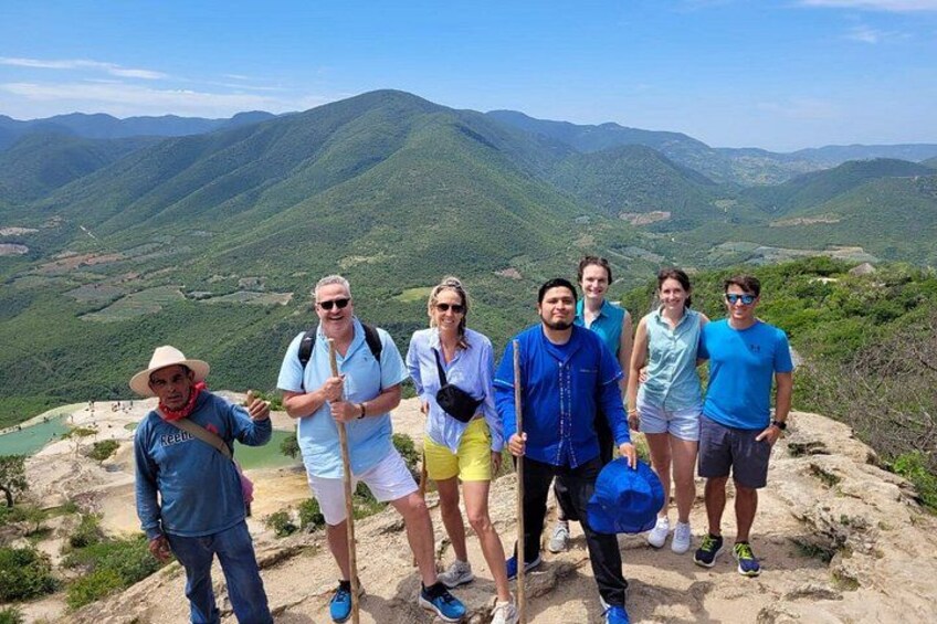 A group of people standing on a mountain ridge with a valley in the background. 1