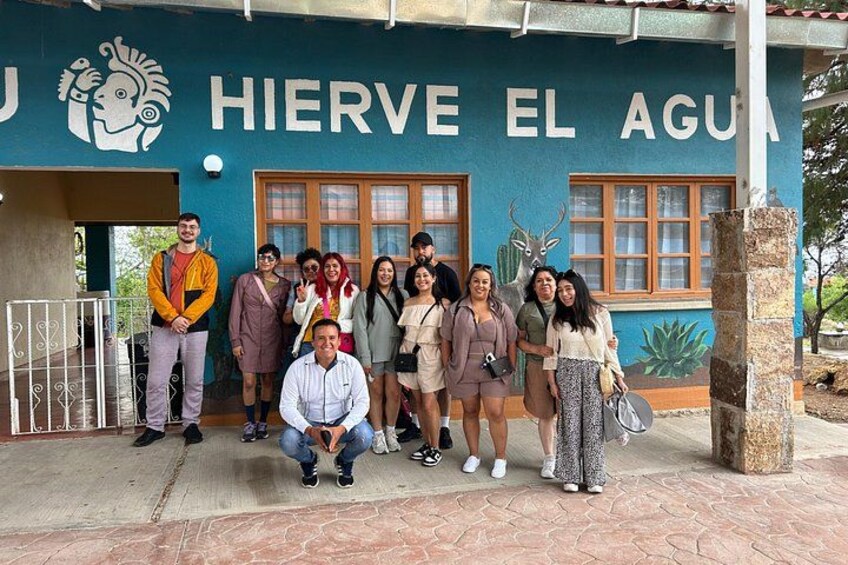 A group of people in front of a building with the sign 'HIERVE EL AGUA'. 5
