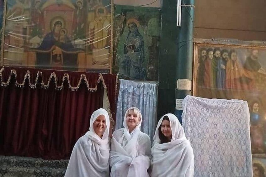 Tres personas con túnicas blancas sentadas frente a un iconostasio religioso con pinturas religiosas. 5