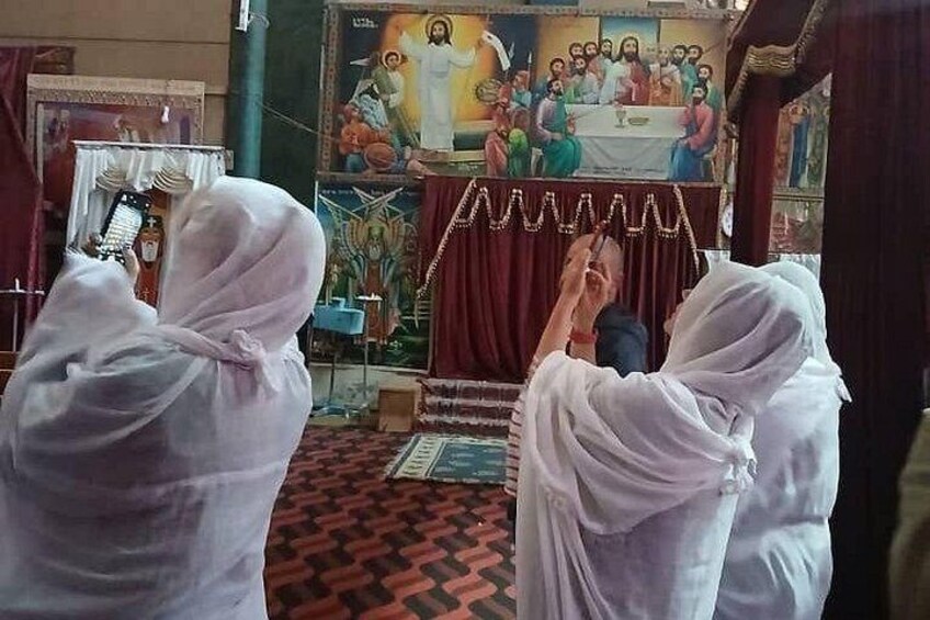 Una ceremonia religiosa con un gran mural de fondo, una alfombra roja y asistentes con túnicas blancas. 4