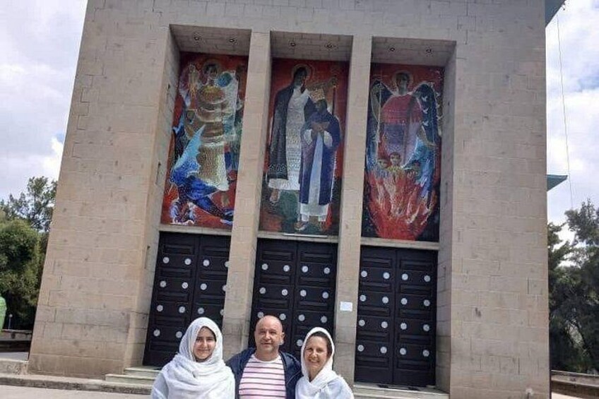 Un edificio con tres grandes puertas y tres murales coloridos sobre ellas. 3