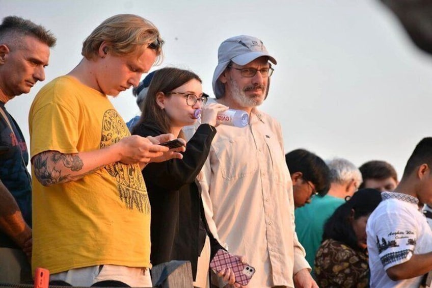 Un grupo de personas al aire libre, algunas usando teléfonos inteligentes. 3