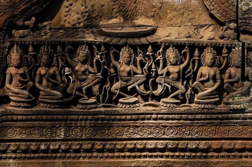 Un grabado de piedra con varias figuras en posición sentada y meditativa, con diseños intrincados y una estructura escalonada al fondo. 5