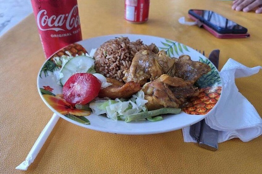 Un plato de comida con arroz, pollo y verduras, una lata de Coca-Cola y un teléfono inteligente sobre una mesa. 2