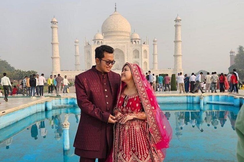 Una coppia in abiti nuziali tradizionali davanti al Taj Mahal. 1