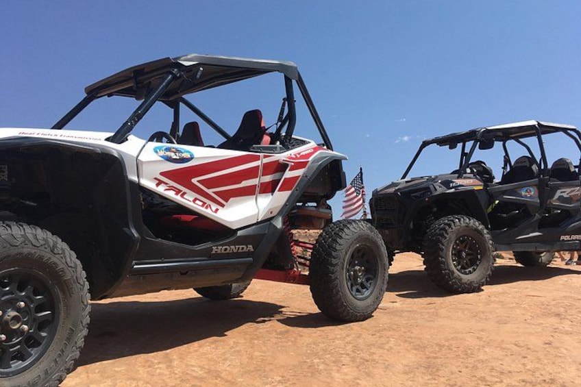 Two off-road vehicles parked on a dirt surface. 5