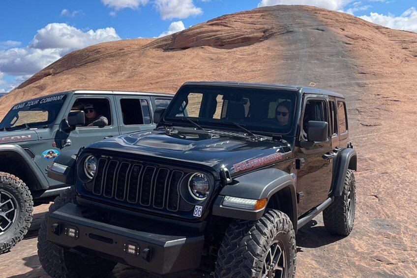 A black off-road vehicle with a rugged design, parked on a rocky terrain with a clear sky. 3