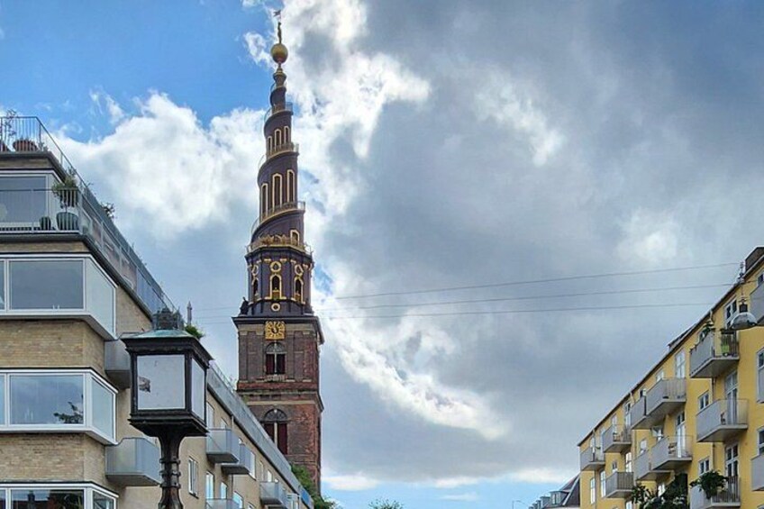 A historic tower with a spire, surrounded by modern buildings. 4
