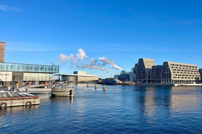 A waterfront with modern buildings, a dock, and a bridge. 3