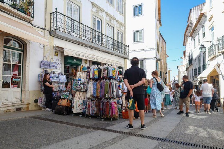 Una calle con tiendas, gente caminando y un edificio con un letrero. 5