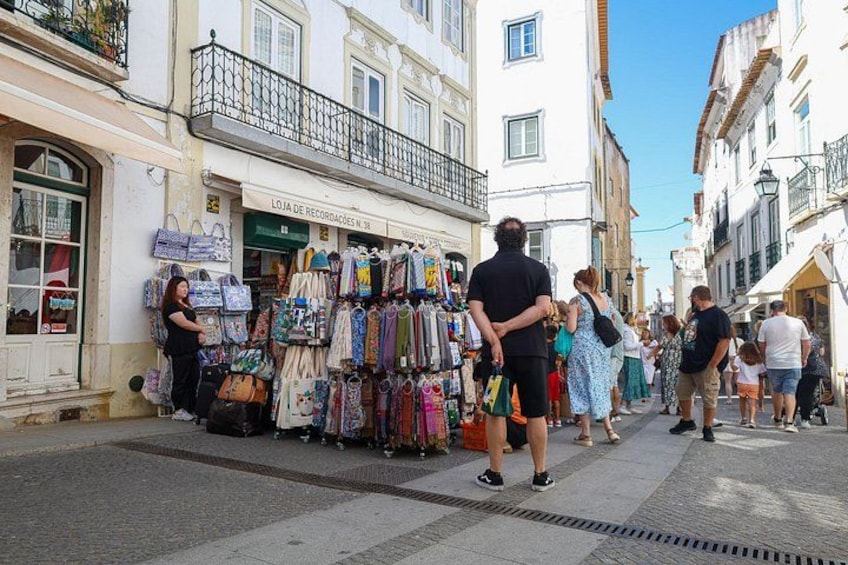 A street with shops, pedestrians, and a building with a balcony. 4