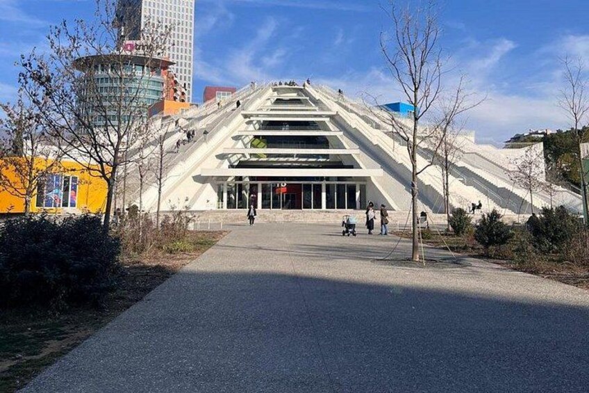 Un edificio moderno con un diseño escalonado único, rodeado de árboles y un cielo despejado. 2
