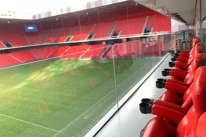 Un estadio con asientos rojos y césped verde. 5