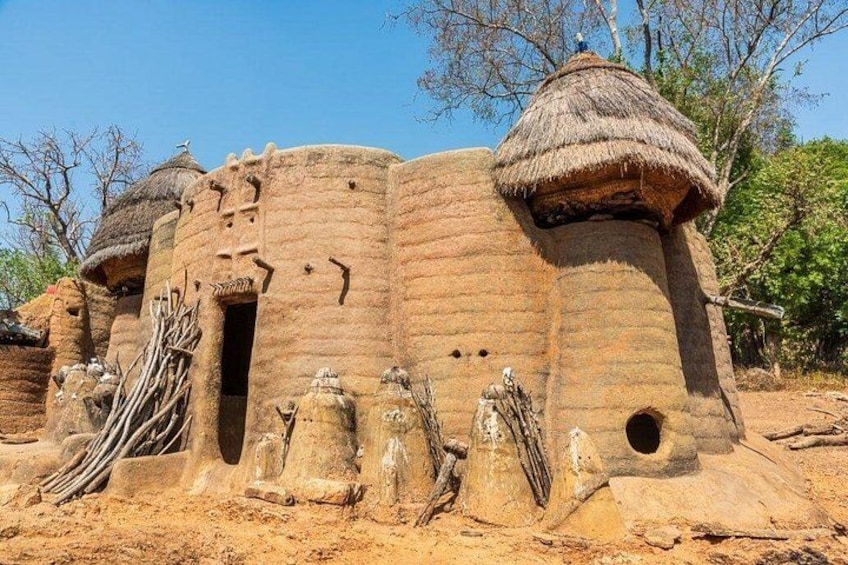 Un bâtiment traditionnel construit en briques de terre et doté d’un toit de chaume, entouré d’un paysage naturel. 1