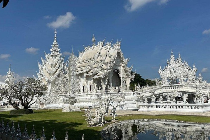 Un complesso di templi bianco e decorato, con numerose pagode e uno stagno riflettente. 4