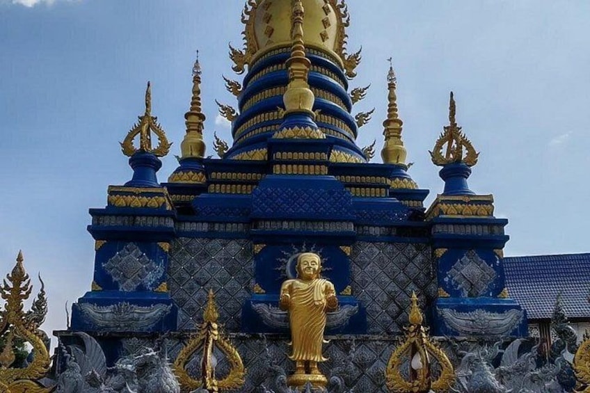 Un tempio con una statua dorata in primo piano, architettura blu e oro, e decorazioni elaborate. 5