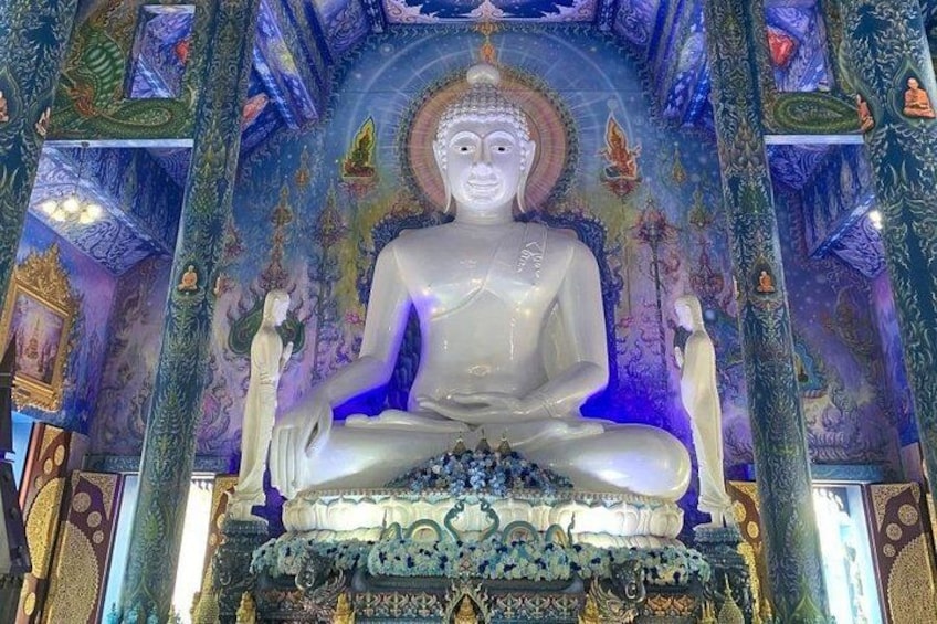 Un'imponente statua seduta in un tempio, con elaborate decorazioni al soffitto e colonne finemente ornate. 1