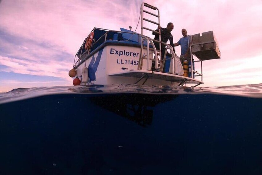 Un bote llamado 'Explorer' con número de registro LL11452, parcialmente sumergido en el agua y con dos personas en la cubierta. 5