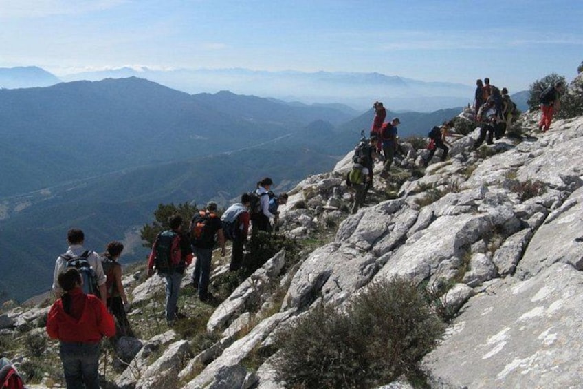 Hikers on a rocky mountain trail with a view of distant mountains. 1